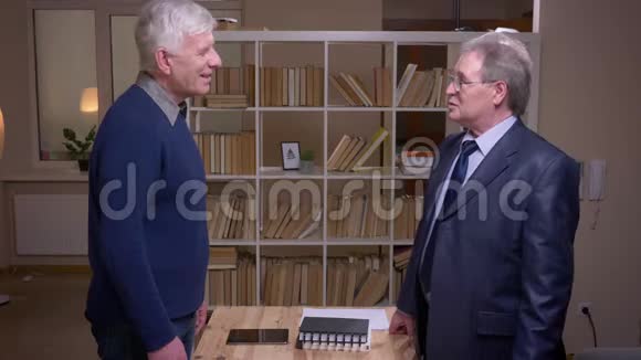 两位老商业伙伴在书架背景上握手签约视频的预览图