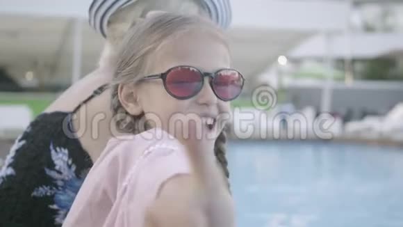 小可爱扎着小辫子成熟的女人坐在池边在镜头里微笑露出拇指视频的预览图