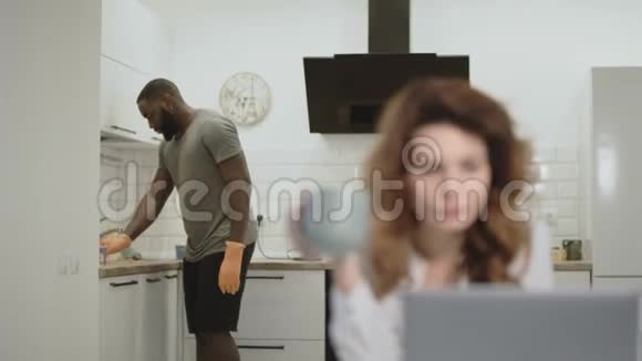 开放式厨房的黑人清洁桌子漂亮女人喝着早咖啡视频的预览图