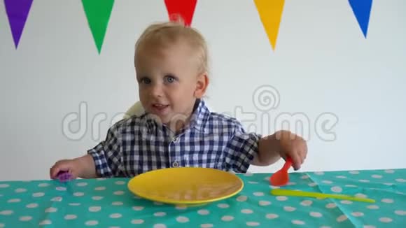 饥饿的男孩用叉子和勺子坐在前面的空盘子里万向节运动视频的预览图