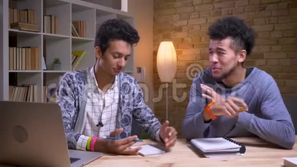 非洲裔美国和印度男性学生的特写镜头讨论一个项目一起愉快地笑在一起用在视频的预览图