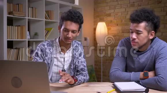 非裔美国和印度男生的特写镜头一起讨论一个项目一种是在笔记本电脑上使用视频的预览图