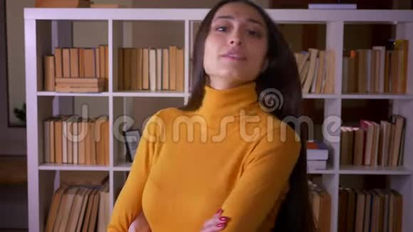 在图书馆里深色头发的女老师在镜头前调情地眨着眼睛显得既可爱又漂亮视频的预览图