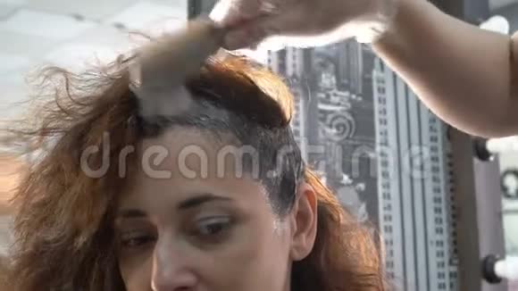 在染发过程中理发师对一位东方国籍的女孩的头发涂上油漆视频的预览图