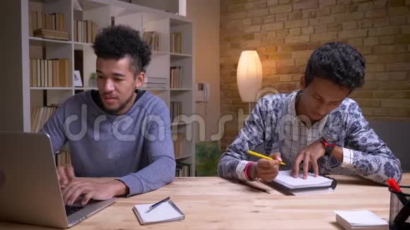 非裔美国和印度的男学生一起做一个项目的特写镜头一个是在笔记本电脑上打字视频的预览图