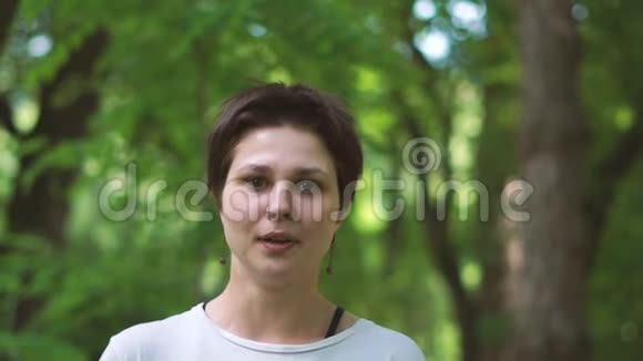 一个年轻的黑发女人快乐地笑在一个绿色的树林在夏天的斯洛文尼亚视频的预览图