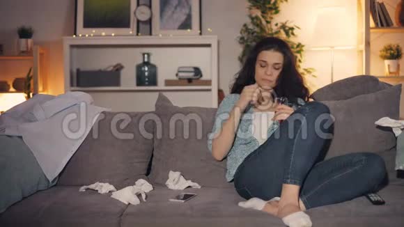 不高兴的年轻女人在家里用智能手机看电视哭着喝酒视频的预览图