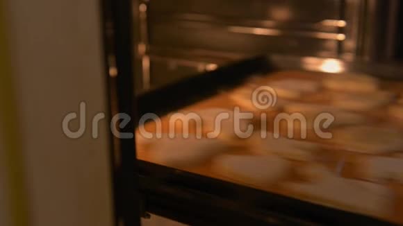 带粉红色指甲的女性手把烤盘和饼干放在烤箱里特写视频的预览图