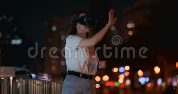 夜城里戴着虚拟现实眼镜的年轻女子手忙脚乱视频的预览图