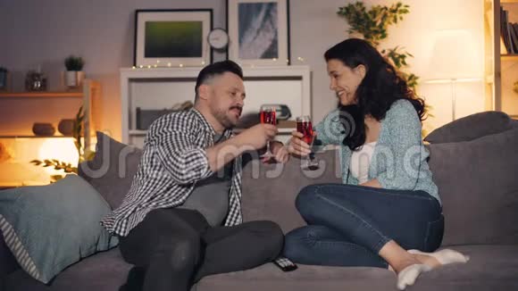 男人和女人说话碰杯喝着酒坐在家里的沙发上视频的预览图