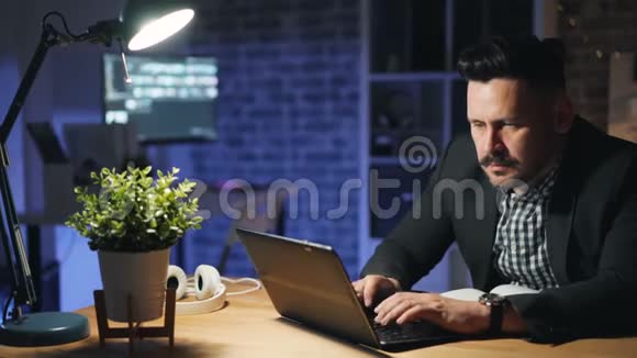 男性员工使用笔记本电脑晚上加班工作忙于项目视频的预览图