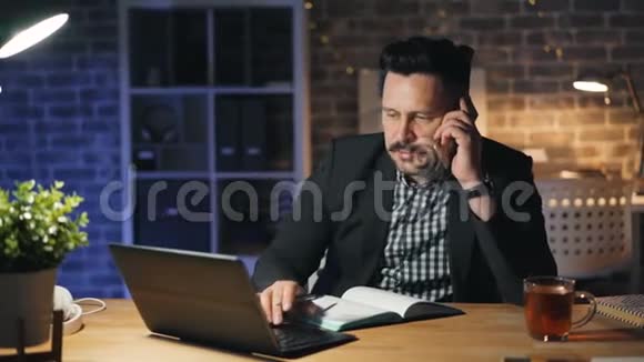 严肃的上班族在晚上用手机和笔记本电脑聊天视频的预览图