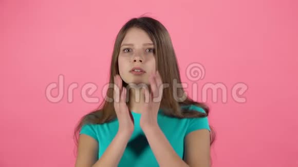 小女孩害怕把她的脸藏在粉红背景的工作室里慢动作视频的预览图