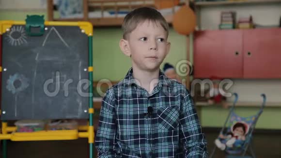一个穿格子衬衫的男孩坐在相机前的椅子上衣服上有麦克风回答问题视频的预览图