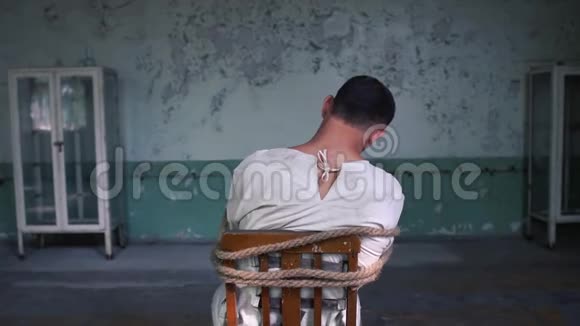 在破旧的房间里一个疯子坐在破旧的蓝色椅子上视频的预览图