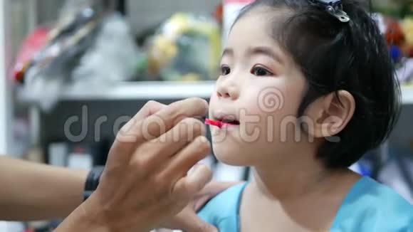 可爱的亚洲小女孩接受一个专业使用小油漆刷涂唇彩视频的预览图