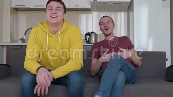 两个人在笑有趣的年轻人坐在沙发上笑得很厉害视频的预览图