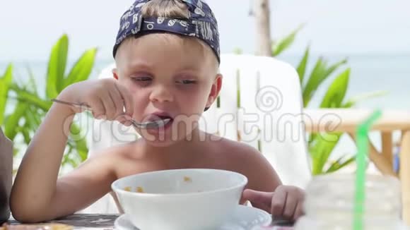 小男孩在户外吃粥在海滩上吃粥的男孩视频的预览图