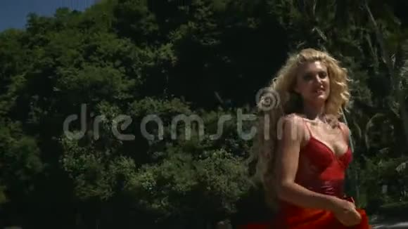 年轻的积极女性金发飘逸的红色长裙视频的预览图