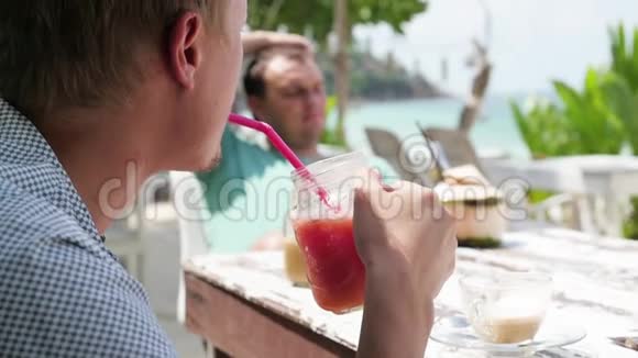 海滩上的夏日水果鸡尾酒两个朋友在海滩上的咖啡馆喝鸡尾酒鸡尾酒和椰子视频的预览图