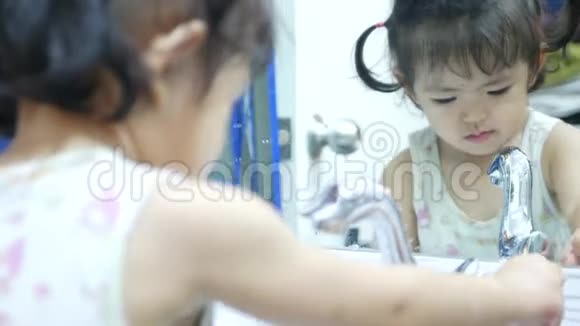小亚洲女孩喜欢打开水龙头玩水在镜子前洗手视频的预览图
