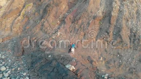 空中射击镜头远离站在巨大岩石底部的男人和女人BenijoTenerife视频的预览图