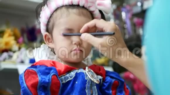可爱的亚洲小女孩接受专业化妆眼影和眉毛刷子视频的预览图