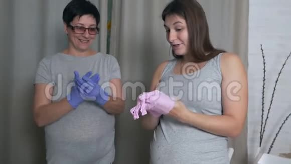 妈妈和怀孕的女儿戴上手套在家庭厨房做饭视频的预览图