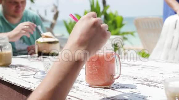 海滩上的夏日水果鸡尾酒两个朋友在海滩上的咖啡馆喝鸡尾酒鸡尾酒和椰子视频的预览图