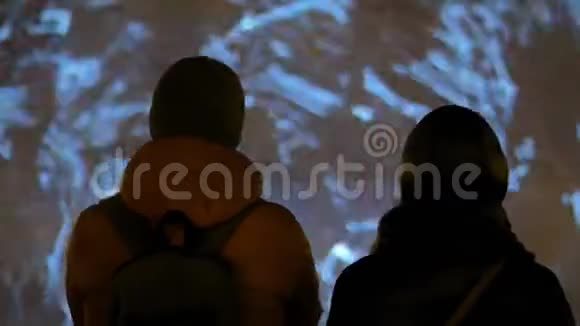 女人和男人欣赏多媒体投影屏幕上的数字艺术视频视频的预览图