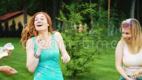朋友们在霍利节向红头发的年轻女子投掷五颜六色的粉末视频的预览图