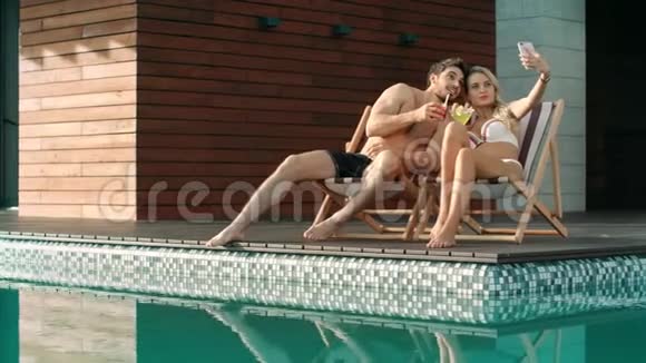亲吻情侣在游泳池附近自拍夏日情侣享受自拍照视频的预览图