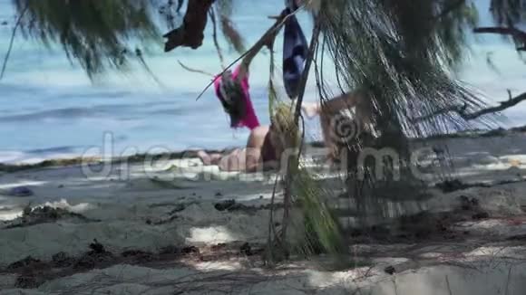 塞舌尔普拉斯林岛两个女朋友躺在棕榈树的树荫下在异国情调的海岸看书视频的预览图