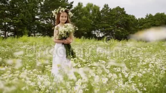 可爱的少女穿着白色连衣裙头上戴花环花束在鲜花草地上视频的预览图