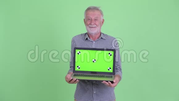 快乐的大胡子男人一边说话一边展示笔记本电脑视频的预览图