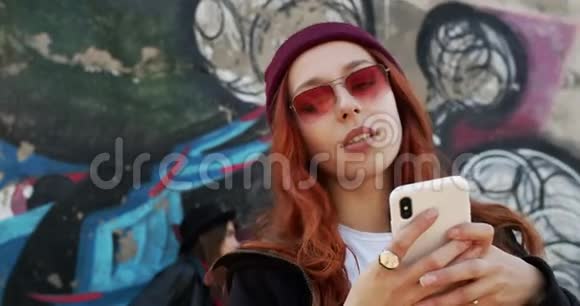 特写一位年轻漂亮的女士穿着时髦的发型红头发戴着太阳镜和帽子打字发短信视频的预览图