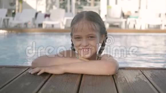 可爱的快乐有趣的女孩戴着黄色太阳镜微笑着看着镜头望着游泳池外抓住了视频的预览图