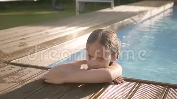 可爱的滑稽女孩扎着辫子笑伸出拇指看着游泳池外抓住边缘普雷特视频的预览图