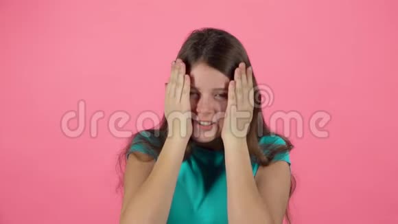 女孩很害怕把她的脸藏在粉红背景的工作室里慢动作视频的预览图