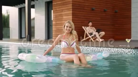 性感的女人在游泳池里玩微笑模特在游泳池放松视频的预览图