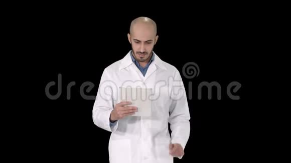 成熟的男性医生拿着数码平板电脑使用它走路阿尔法频道视频的预览图