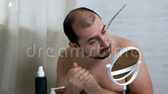 那个人用洗剂擦脸一个英俊的男人照顾他脸上的皮肤在脸上涂上保湿霜视频的预览图