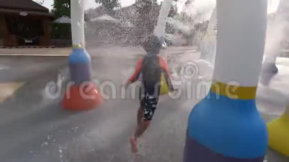 在水上乐园水上游乐园里男孩穿过飞溅喷泉隧道视频的预览图