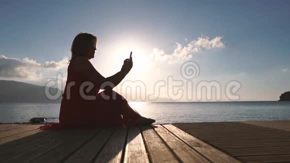 女人在日落时以慢动作点击屏幕使用智能手机视频的预览图