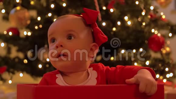 小女孩坐在圣诞树上的礼盒里视频的预览图