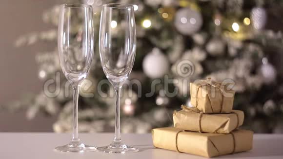 香槟酒正倒入礼品盒附近的两个玻璃杯中圣诞节和新年视频的预览图