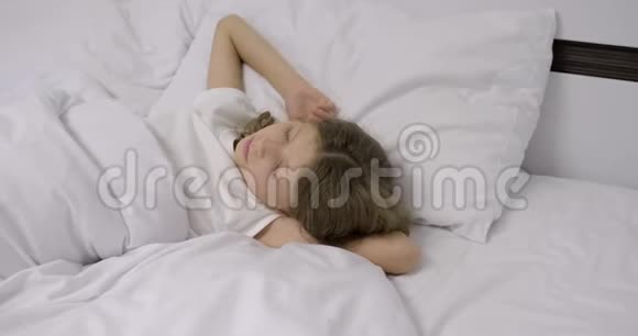 十岁的女孩一头金发睡在枕头上的白床上视频的预览图