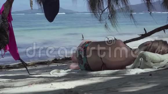 塞舌尔普拉斯林岛可爱的小女孩躺在棕榈树的树荫下在异国情调的海岸听音乐视频的预览图