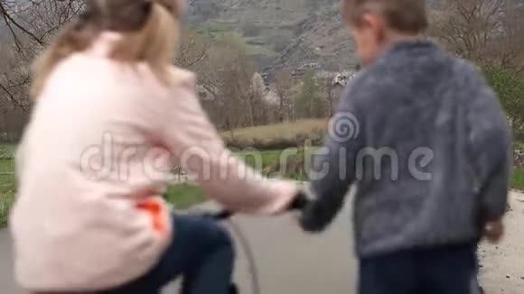 两个孩子用自行车赛跑在乡村风景中跑步视频的预览图