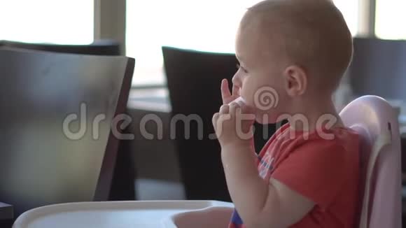 小男孩慢吞吞地坐在高椅上吃香肠视频的预览图